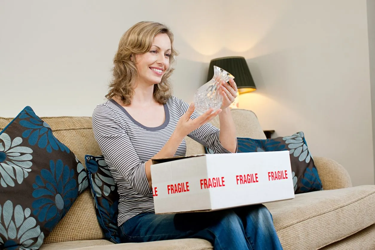 Mature woman opening parcel containing glass vase